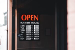 Close-up of an open business hours sign displayed in a shop window.