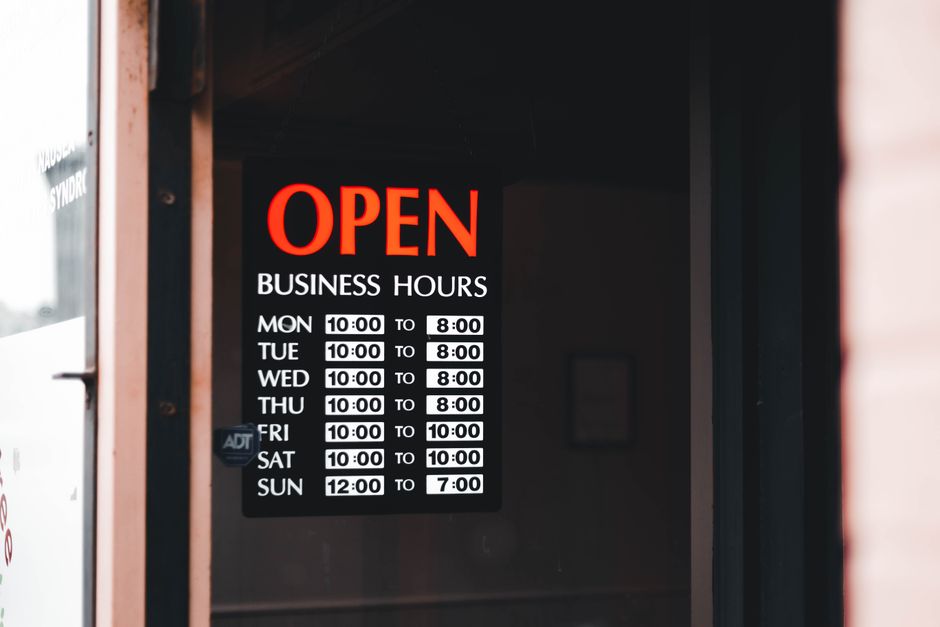 Close-up of an open business hours sign displayed in a shop window.